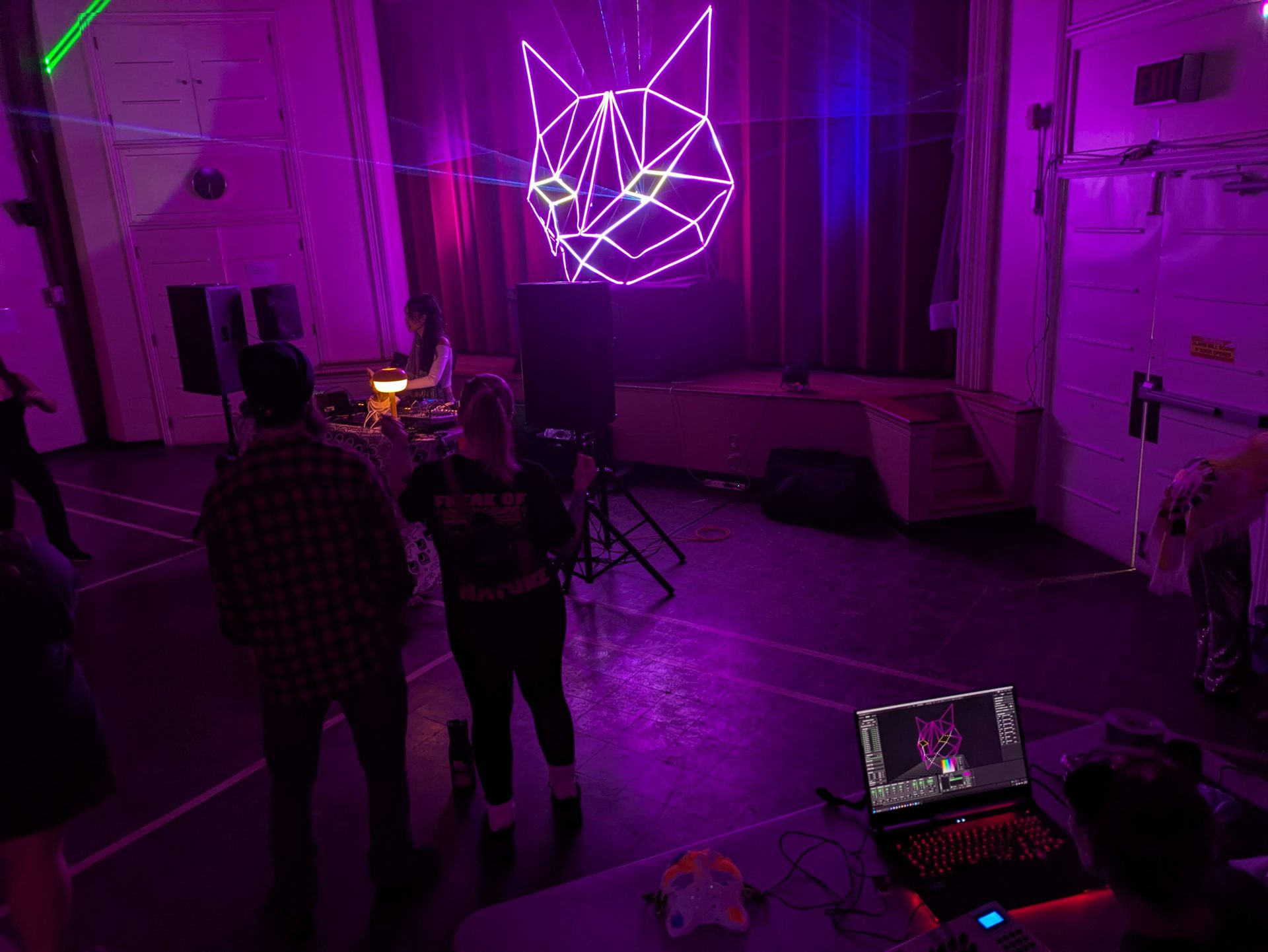The sculpture above the DJ booth with green and blue laser beams cutting across the hall.