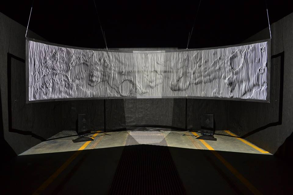 The full installation: a wide semi-circular wire screen in a darkened hall, the surface of Mars projected across it.