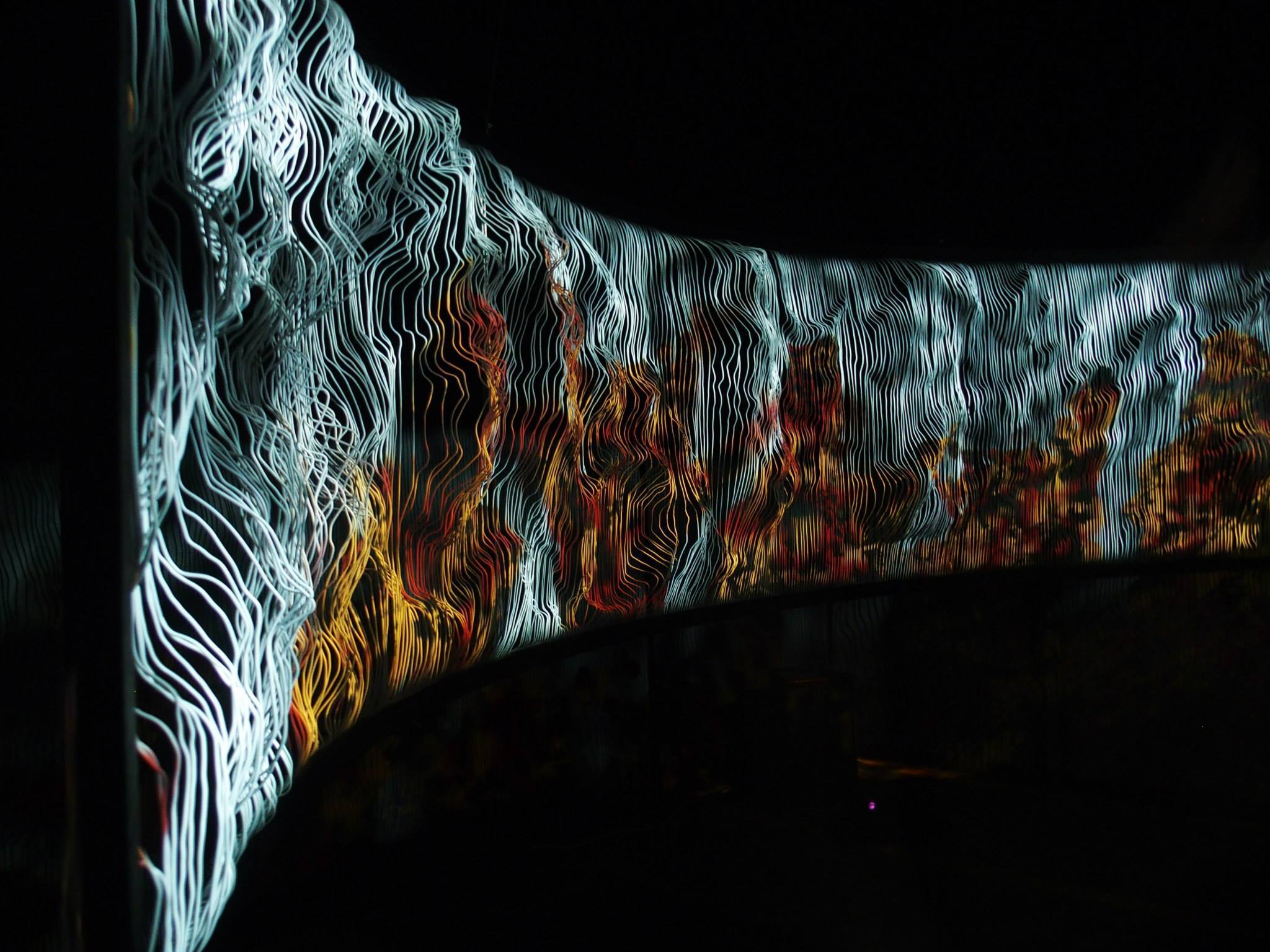 The installation lit in white and orange, the terrain glowing as though fire-lit.