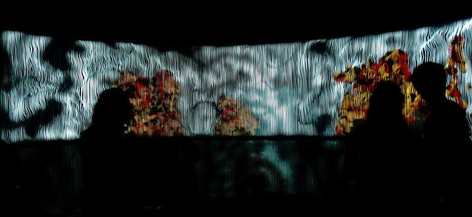 Silhouettes of visitors against the full width of the screen in orange and white.
