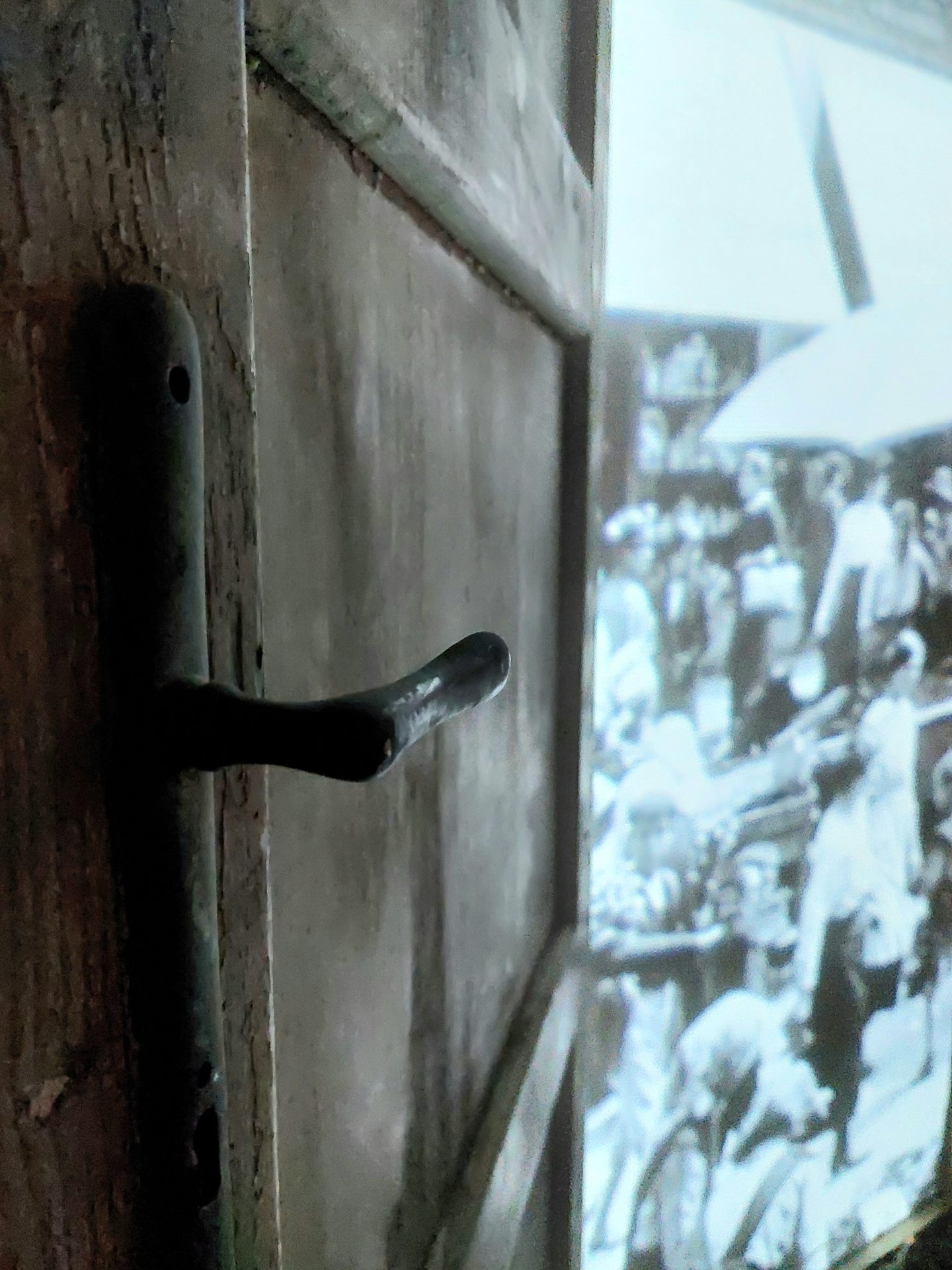 Detail of the weathered handle of one of the doors, the projection glowing behind it.