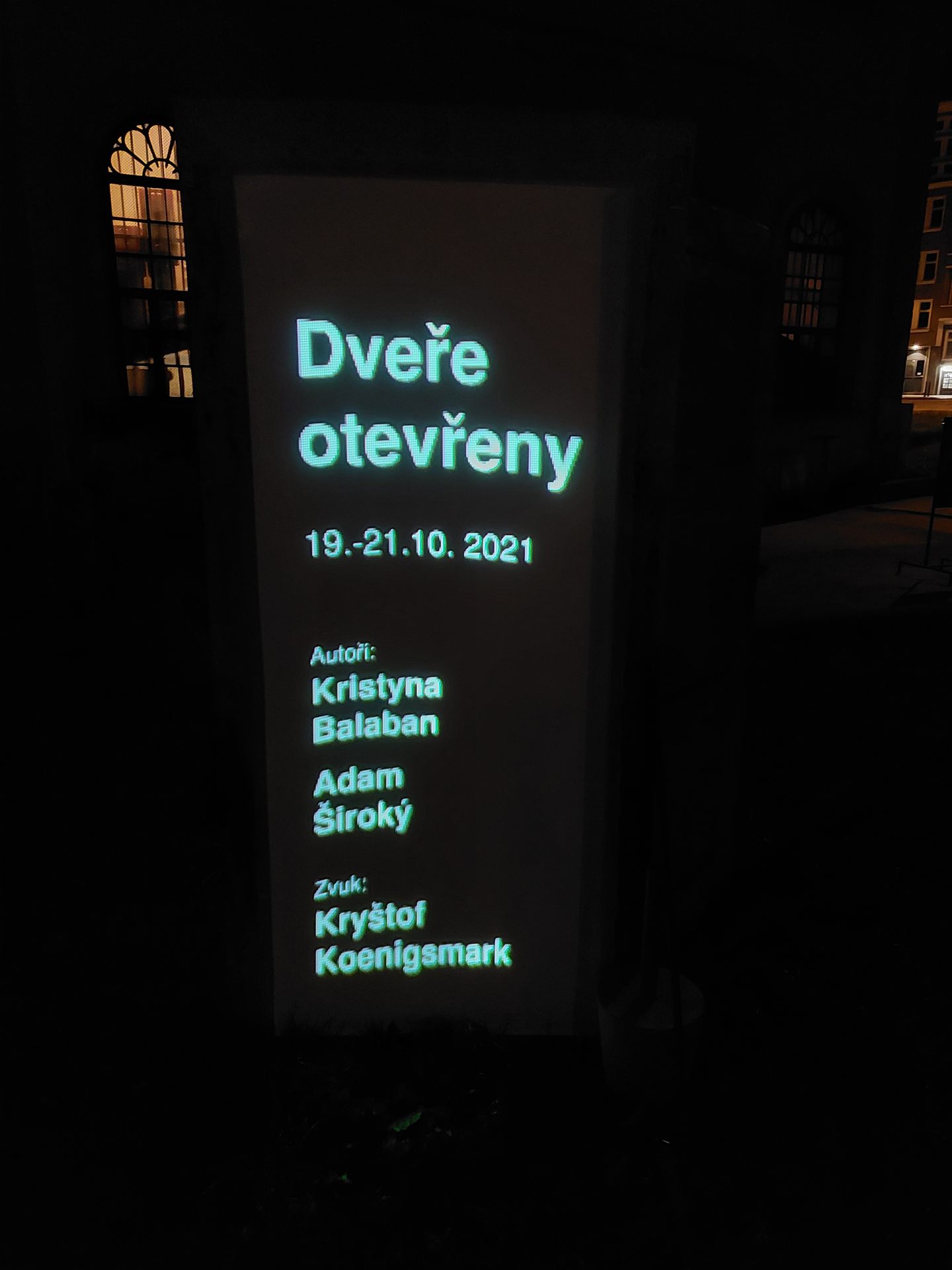 The illuminated credits panel reading “Dveře otevřeny, 19.-21.10.2021”.