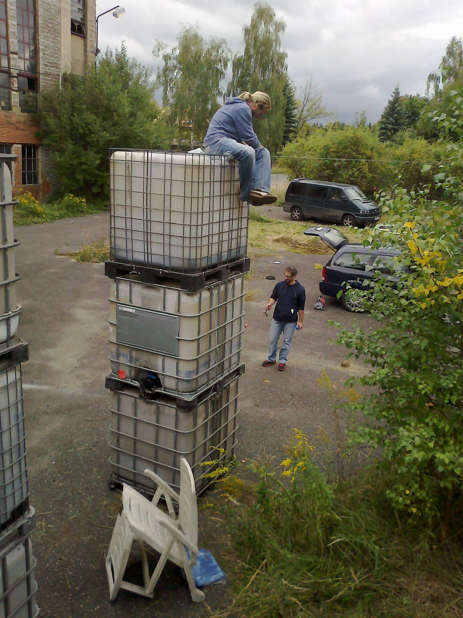 Daytime build: a person sitting on top of the stacked containers during assembly.