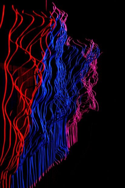 Close view of red, blue and pink light running along the hanging wires.