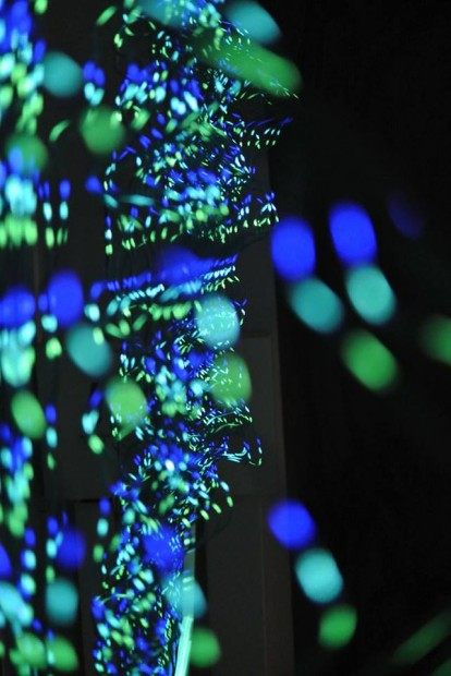 Points of green and blue light scattered along the wires like bokeh.
